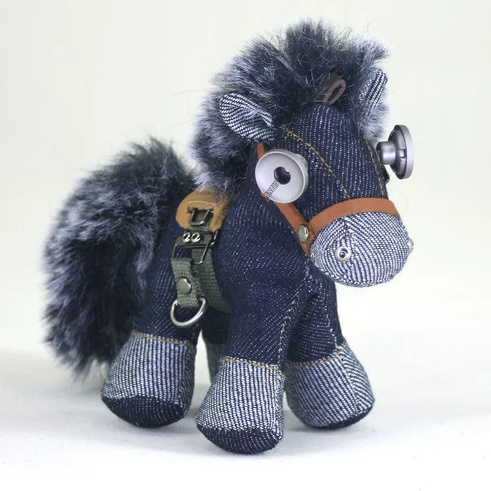 Stylized denim horse ornament in dark indigo with tan leather tack and weathered metal hardware. Dark aesthetic artisan craft, folk art decor.
