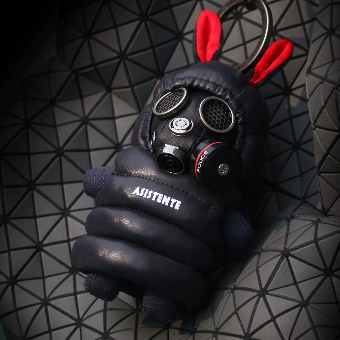 Gothic bunny figure in dark quilted jacket with detailed gas mask and red-accented ear tips. Dark techwear aesthetic, artisan designer toy.