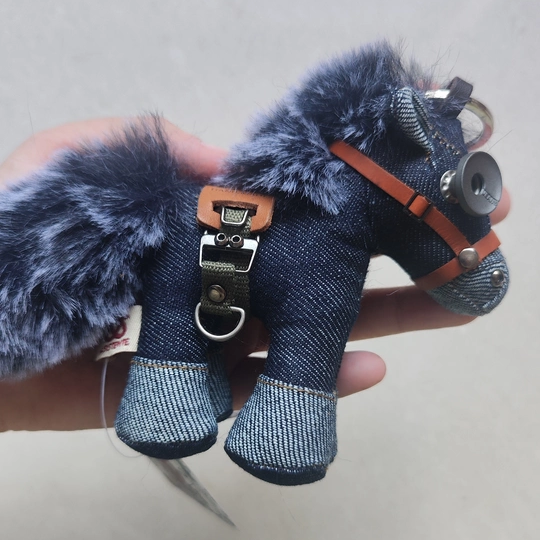 Denim horse keychain with distressed metal button eyes and leather tack details. Gothic artisan craft, dark folk art collectible.