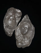 Three sculptural silver-toned baroque pearl pendant reliefs showing three different facial expressions—curly hair, closed eyes, and open eyes—arranged in a triangular composition against a black background