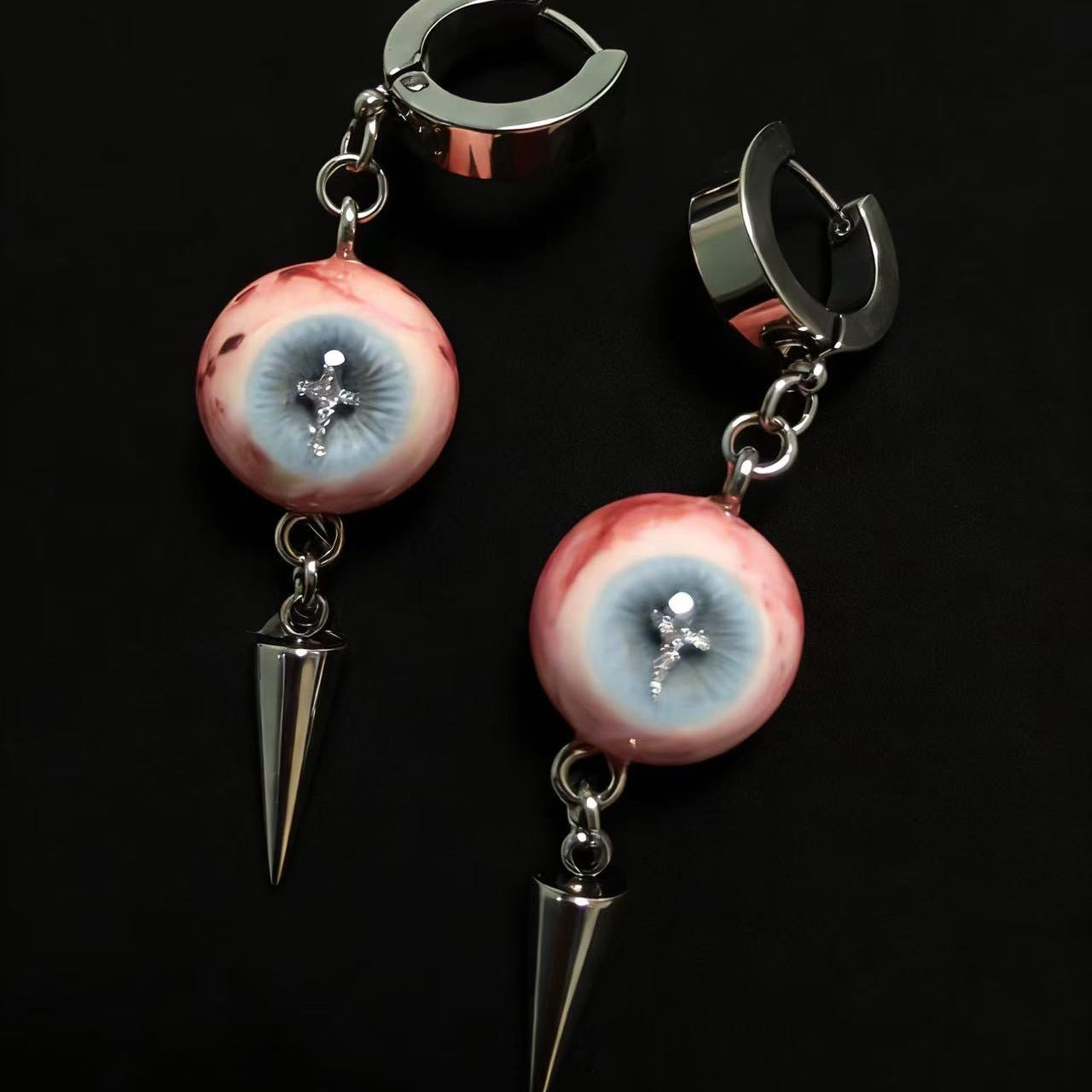 Gothic cross eyeball spike drop earrings on black background