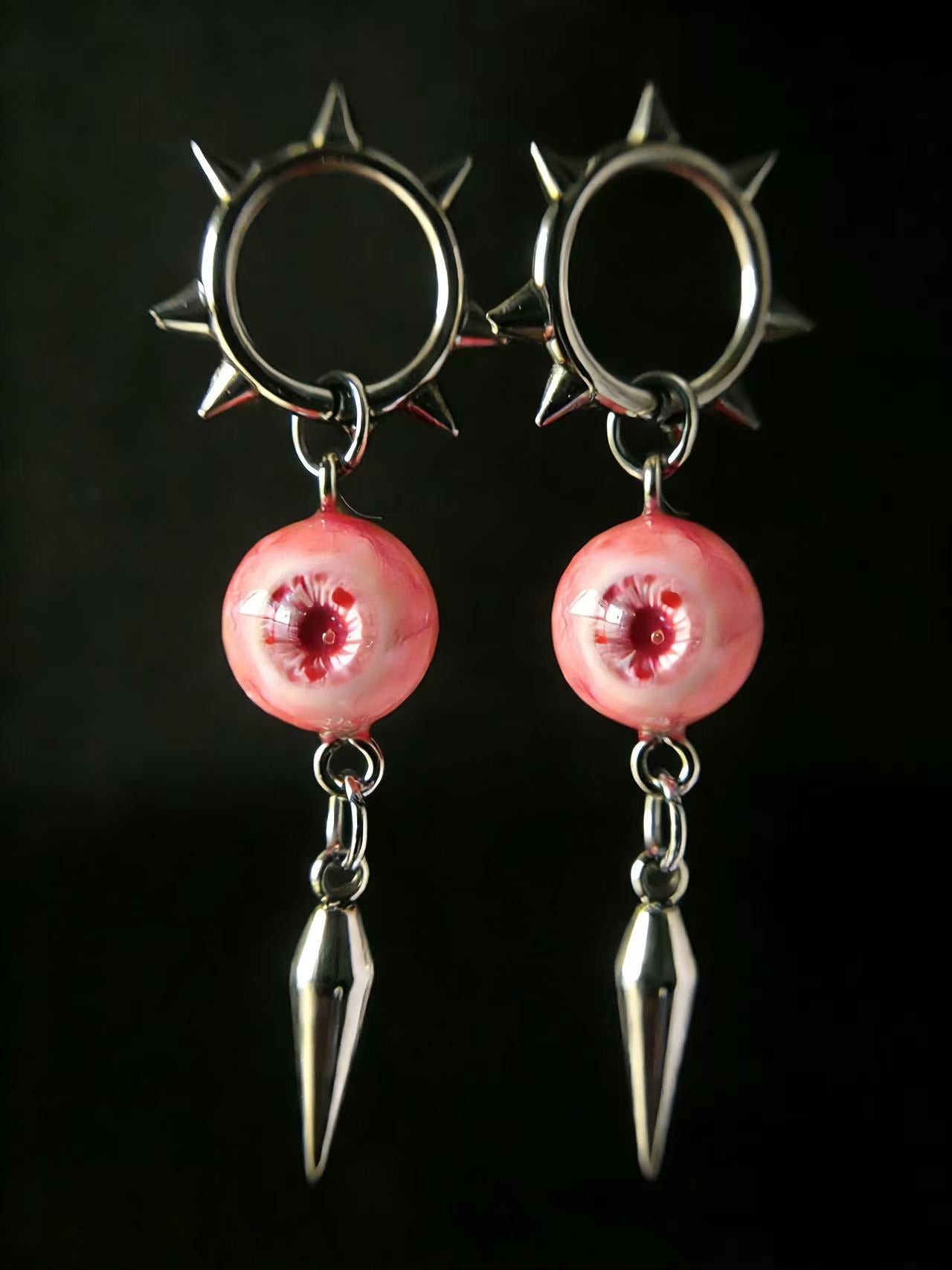 Pink gothic spiked eyeball earrings with metal spike drop on dark background