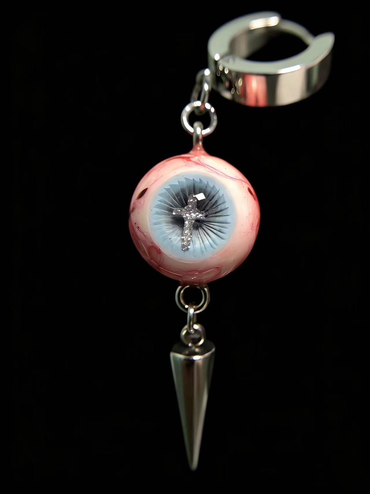 Close-up of gothic cross eyeball spike earrings showing detailed iris texture and polished metal spike