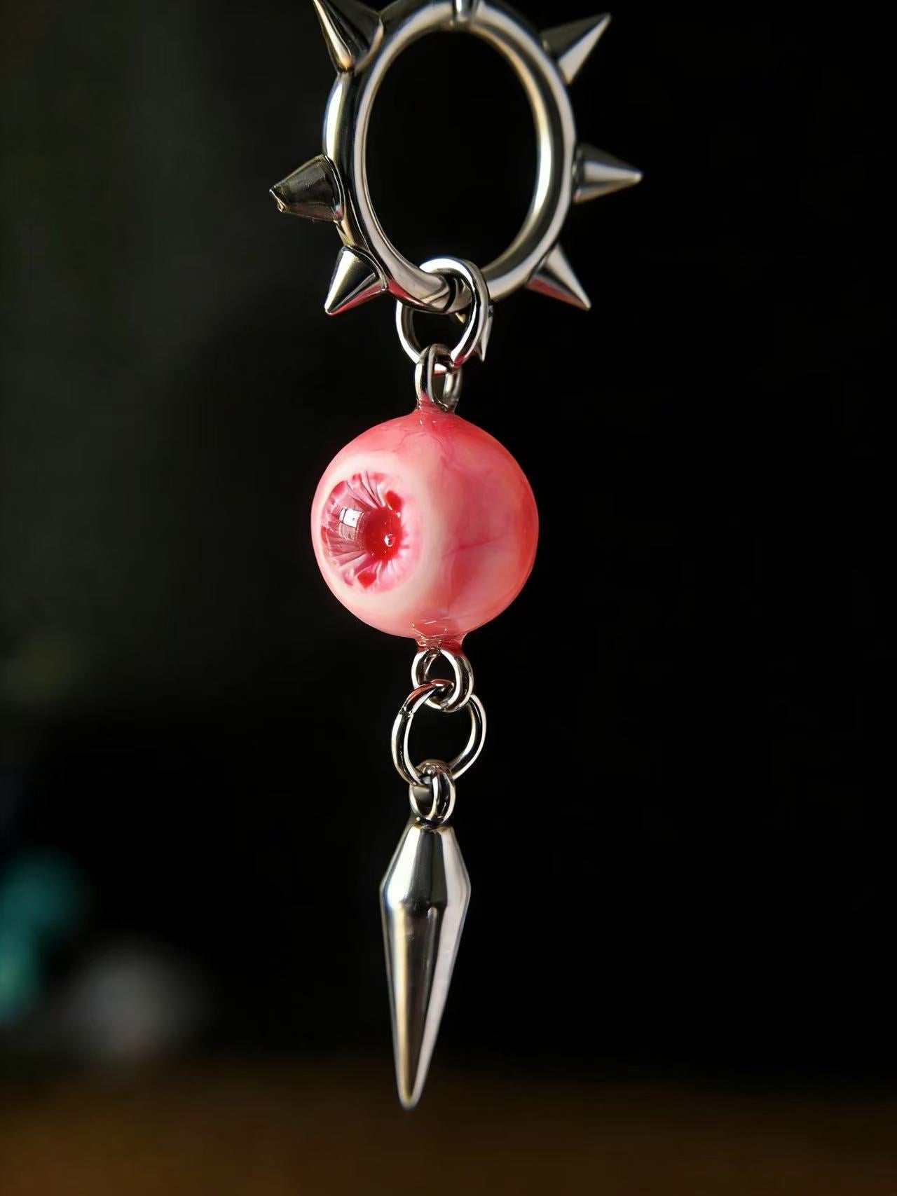 Close-up of pink eyeball gothic earrings showing detailed resin texture and metal spikes