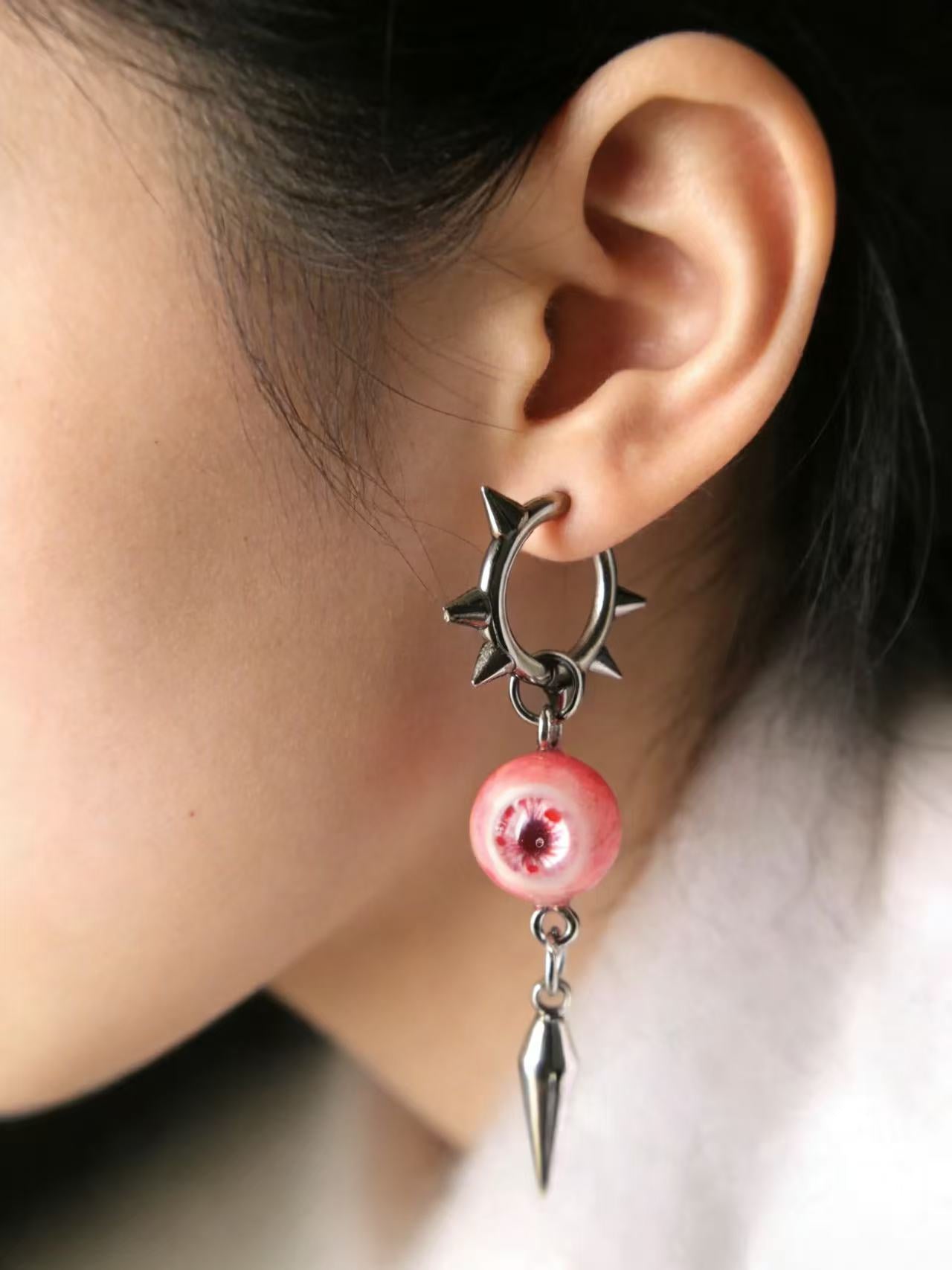 Dark aesthetic punk earrings with pink eyeball charm and silver spike hardware