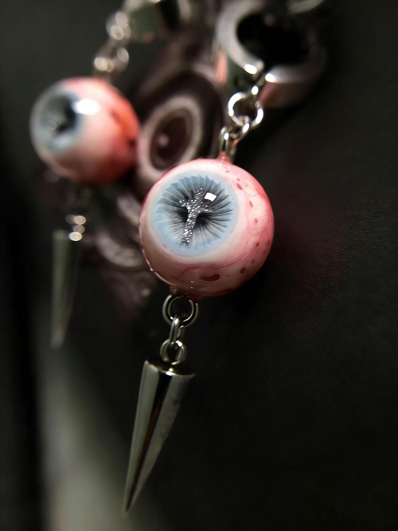 Macro view of handmade eyeball drop earrings with cross pupil design and titanium steel hoop