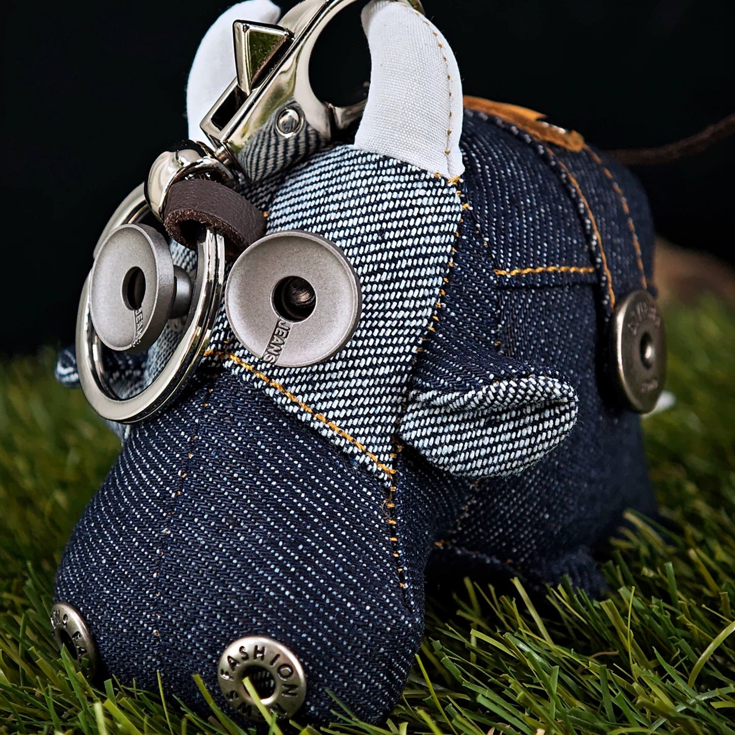 Peculiar miniature ox figurine in dark indigo with golden stitching accents. Gothic artisan keychain, dark folk art collectible.
