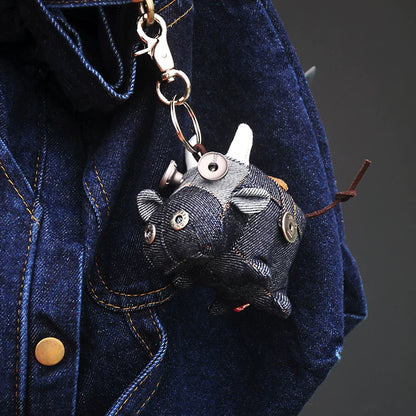 Peculiar artisan ox keychain in dark indigo with metal hardware accents. Gothic folk art style, macabre collectible.