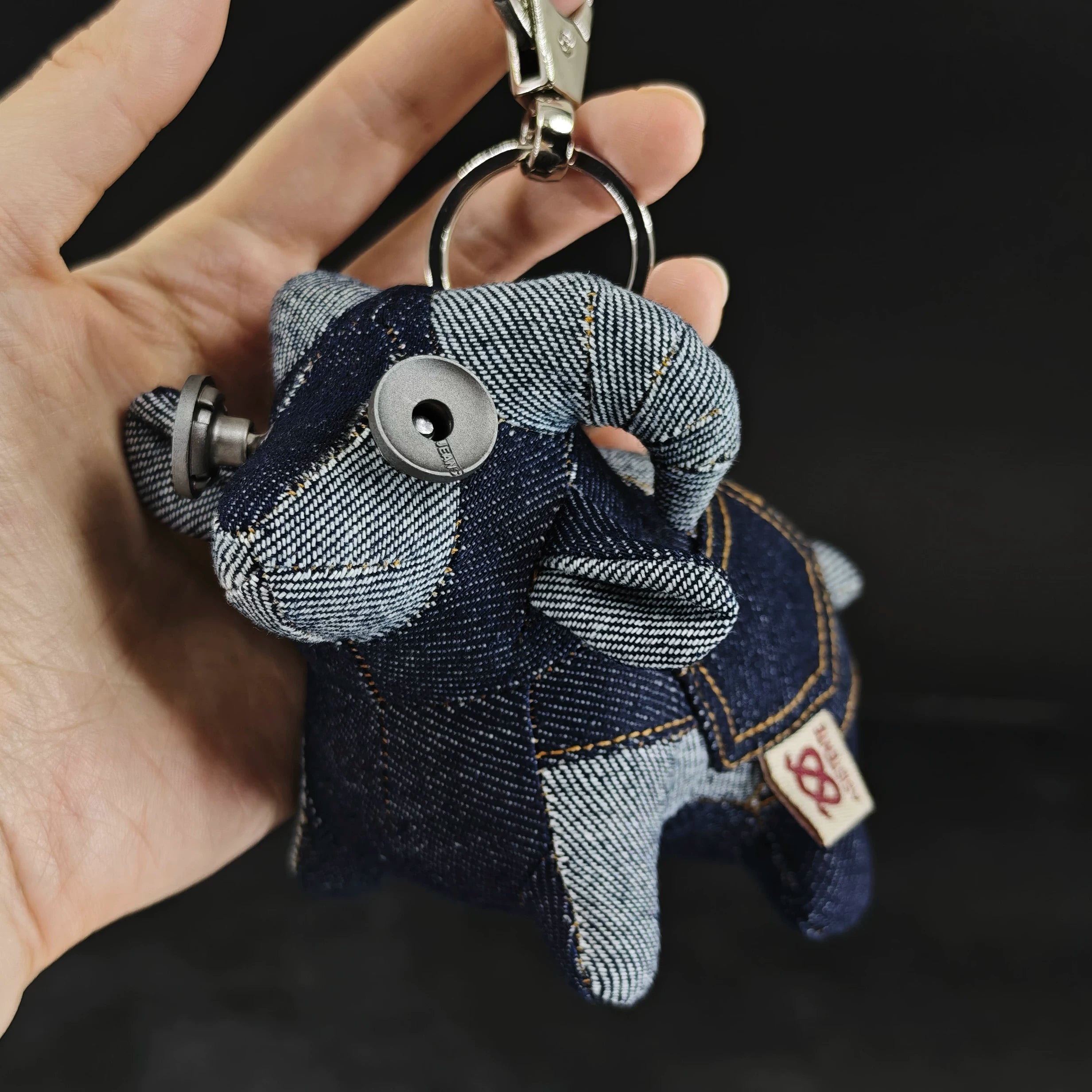 Indigo denim lamb figurine with curly texture and blue-gray fabric. Dark folk art artisan keychain, macabre collectible.