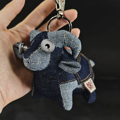 Indigo denim lamb figurine with curly texture and blue-gray fabric. Dark folk art artisan keychain, macabre collectible.