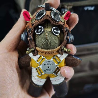 Aviator Pilot Dog Coffee Version — Mini Plush Keychain — backpack clasp view showing waterproof fabric shell, TURN TO UNLOCK metal buckle, PRESS TO RELEASE closure detail — Awhisker