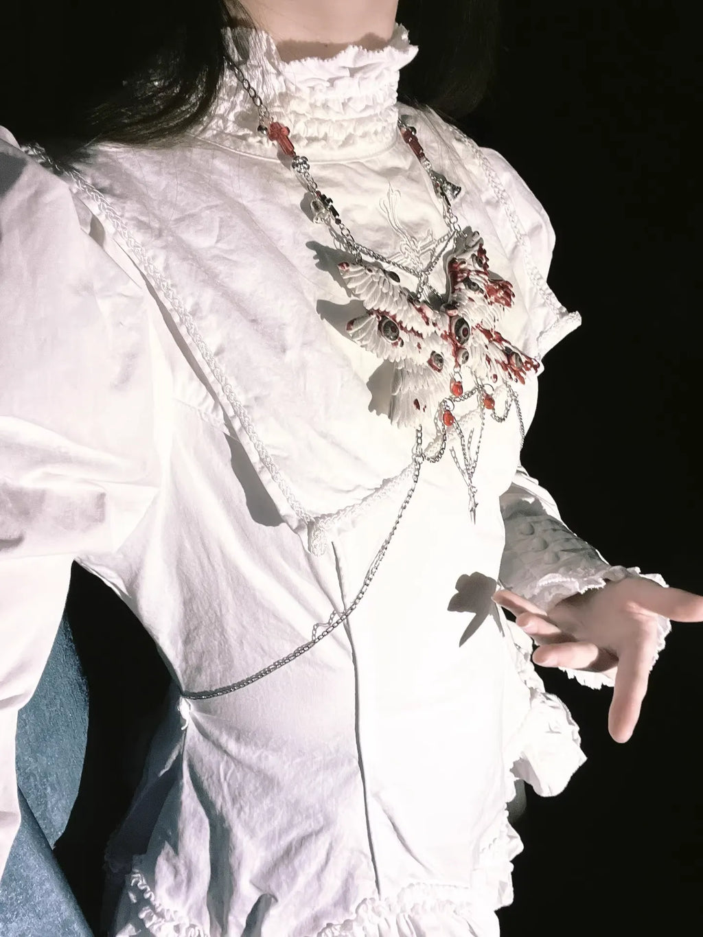 Angel cage eyeball wing body chain on white gothic dress, person with outstretched hand, dark background