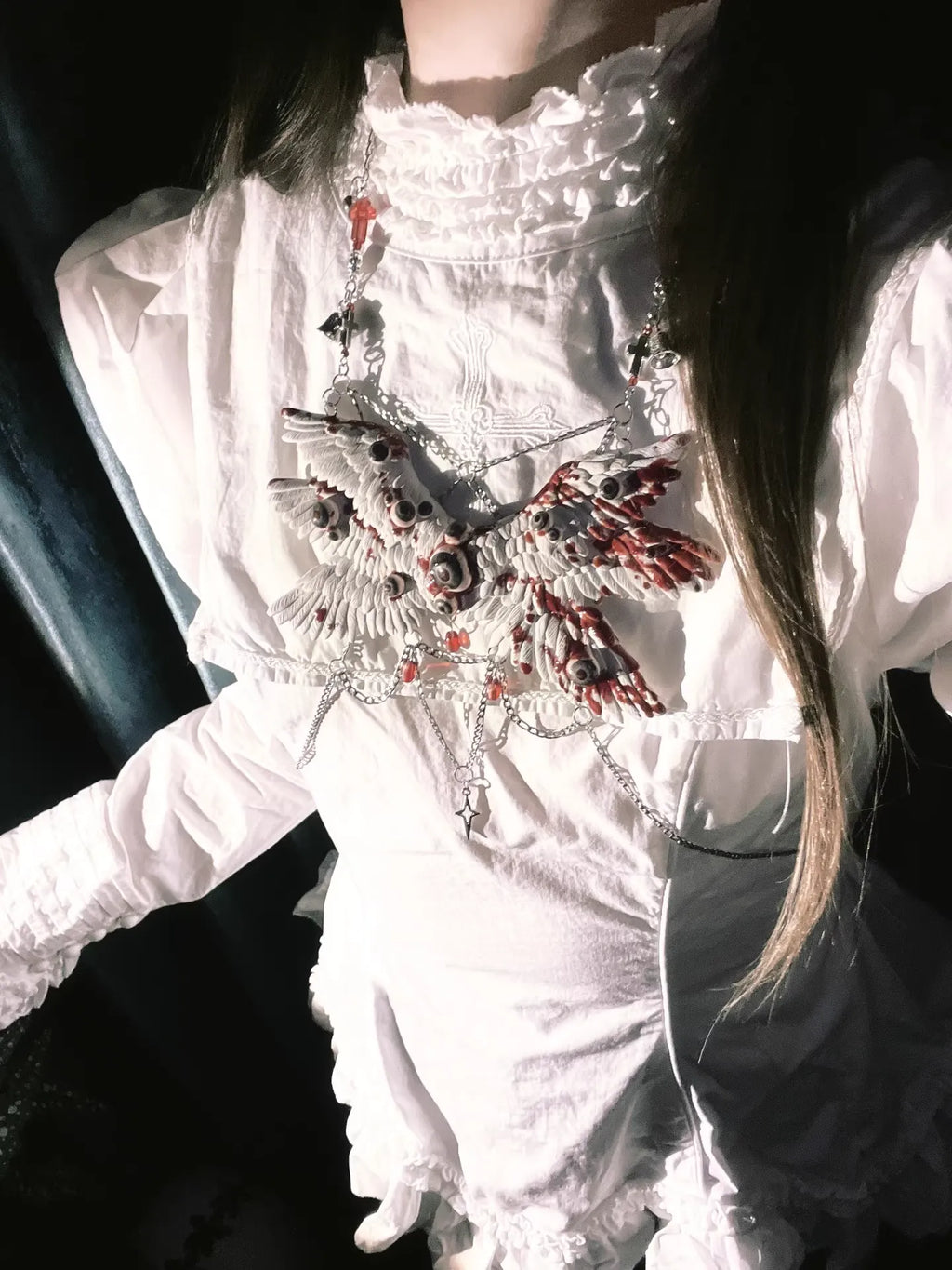 Angel cage body chain on white ruffled gothic dress, side-lit against solid dark background