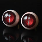 Close-up of crimson magma slit pupil eyeball cartilage studs, pair on black