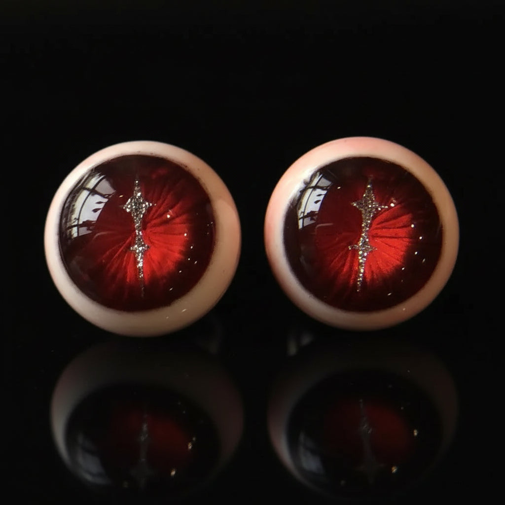 Pair of crimson magma slit pupil eyeball cartilage studs on solid black background