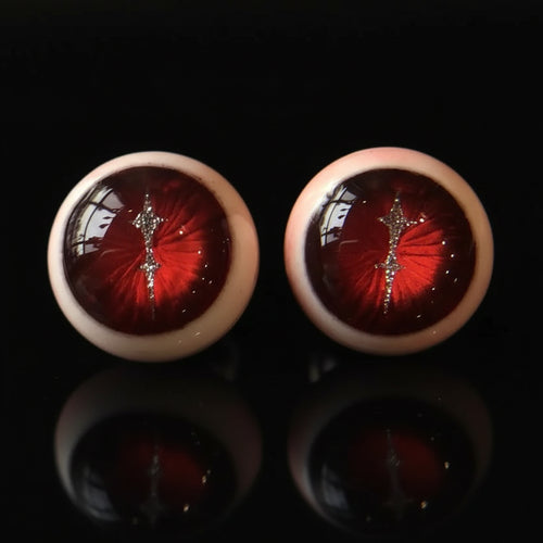 Pair of crimson magma slit pupil eyeball cartilage studs on solid black background