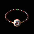 Single strand Cthulhu eyeball bracelet, deep red garnet beads, green accent, gold spacers, focal eyeball on black