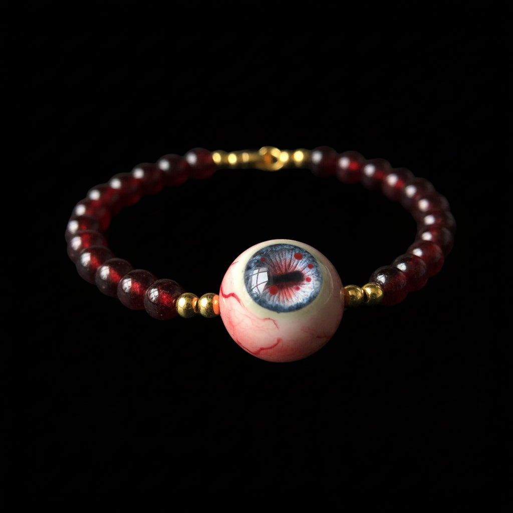 Single strand Cthulhu eyeball bracelet, deep red beads, gold spacers and clasp, focal eyeball on black