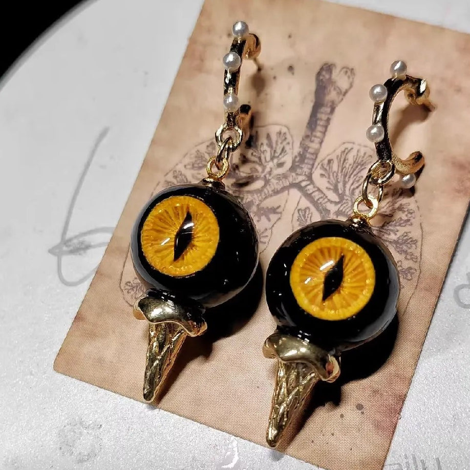 Pair of obsidian cat eye abyssal spike drop earrings on vintage anatomical printed paper