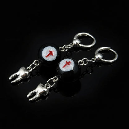 Gothic crimson cross faux eyeball tooth charm drop earrings on solid black background