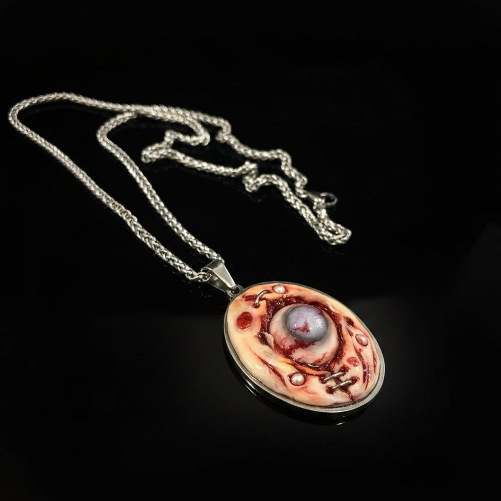 Diagonal view of oval pendant on black textured rope chain, glossy sculpted surface with embedded eyeball and silver staples