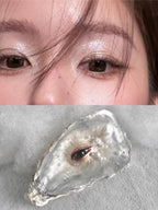 Lovers eye pendant, pale pink sculpted eye, blue iris, baroque pearl drop chains, on black glass plate, dark background