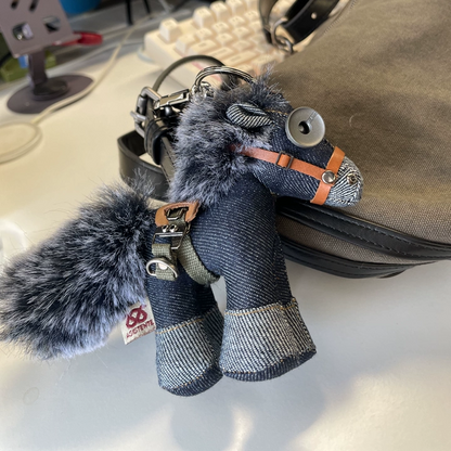 Indigo denim horse with visible stitching and weathered leather accents. Dark aesthetic artisan craft piece, macabre folk art toy.