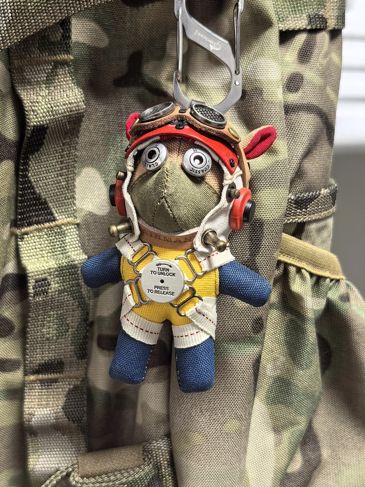 Pilot dog figure in gothic aviator gear with leather jacket and metal goggles. Macabre artisan art toy, dark vintage collectible keychain.