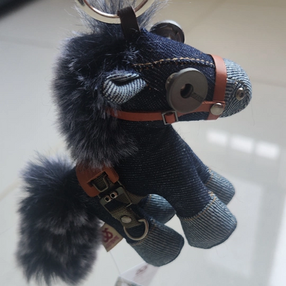 Denim horse showing textural weave and weathered metal buckles. Dark aesthetic artisan craft, macabre folk art piece.