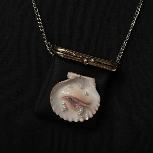 A black pebbled leather kiss-lock purse with three surreal shell eye embellishments featuring blue irises and white eyelashes, a gold-toned clasp, and a silver chain strap displayed against a dark background